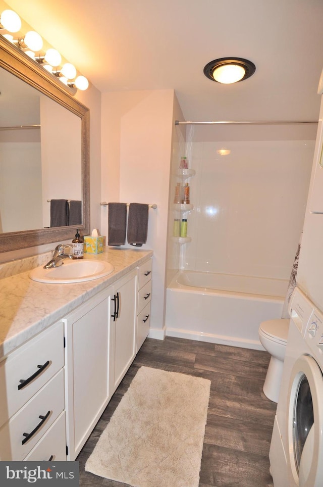 full bathroom with stacked washer and clothes dryer, toilet, bathing tub / shower combination, vanity, and hardwood / wood-style floors