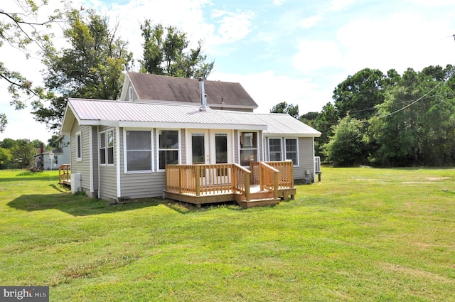 rear view of house with a wooden deck, a lawn, and french doors