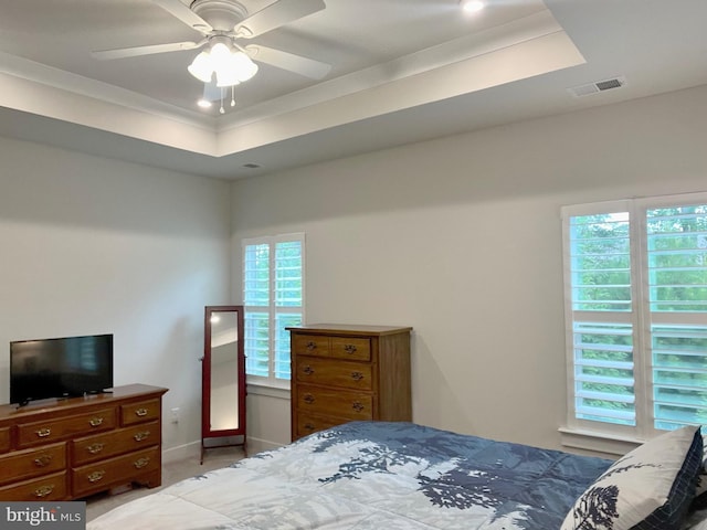 bedroom featuring a raised ceiling, ornamental molding, ceiling fan, and multiple windows