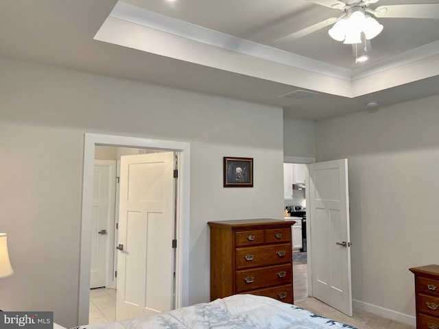 bedroom with ceiling fan, a tray ceiling, and light tile patterned floors