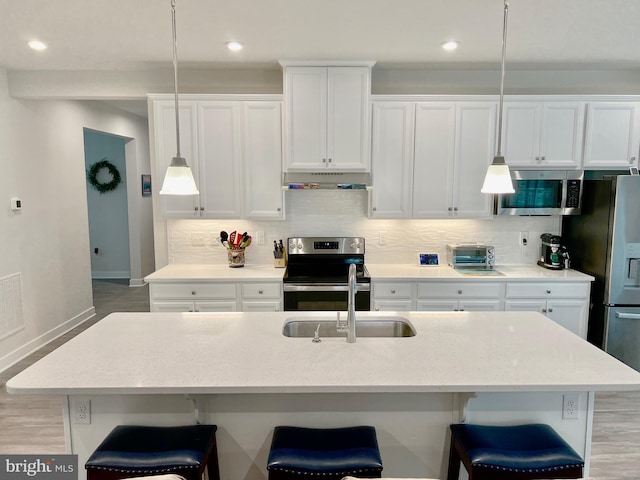 kitchen with hanging light fixtures, a kitchen island with sink, and stainless steel appliances