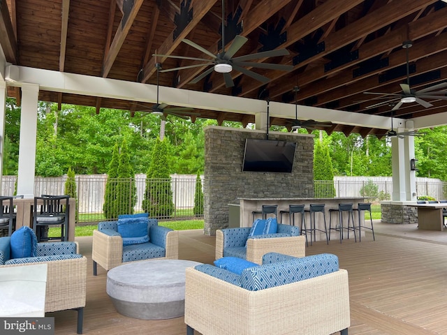 view of patio with a wooden deck, ceiling fan, an outdoor living space, and an outdoor bar