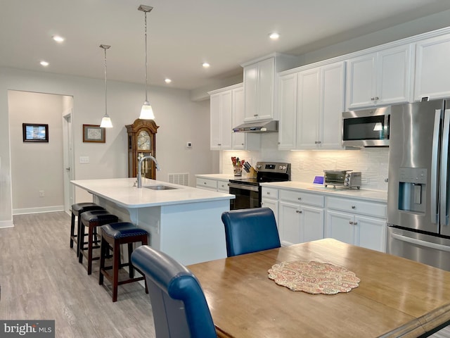 kitchen featuring stainless steel appliances, an island with sink, sink, and white cabinets