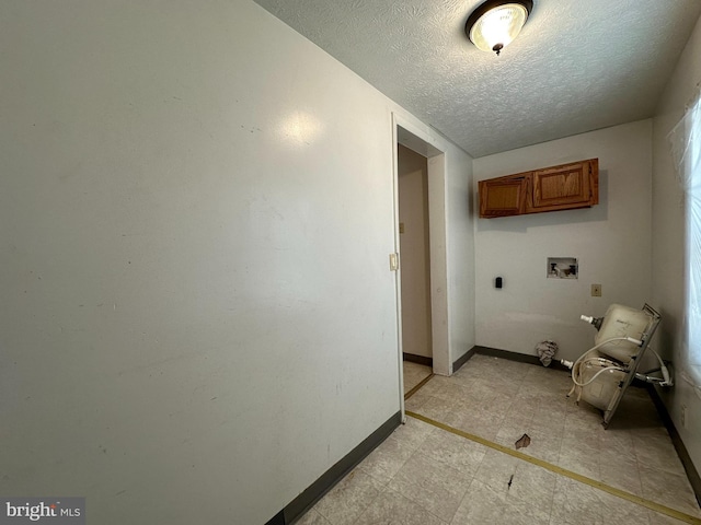 washroom with a textured ceiling, hookup for an electric dryer, hookup for a washing machine, and cabinets