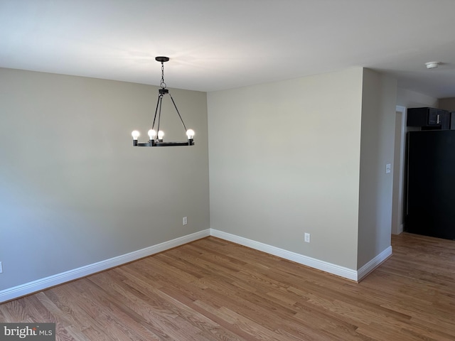 empty room with an inviting chandelier and light hardwood / wood-style floors