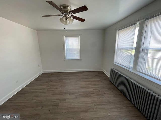 empty room with ceiling fan, radiator, and dark wood-type flooring