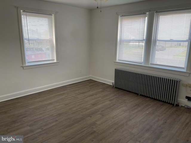 unfurnished room featuring radiator, ceiling fan, and dark hardwood / wood-style floors