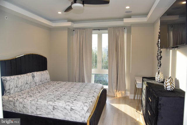 bedroom featuring a tray ceiling, ceiling fan, and light hardwood / wood-style floors