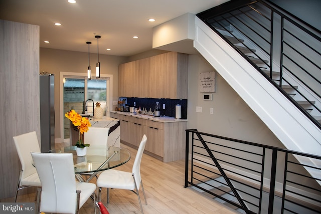 kitchen with light hardwood / wood-style flooring, light brown cabinets, hanging light fixtures, fridge, and decorative backsplash