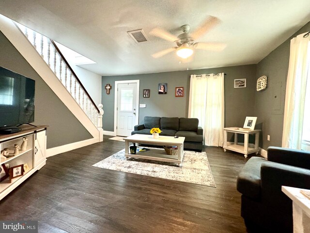 living room with dark wood-type flooring, a textured ceiling, and ceiling fan