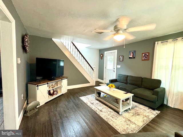 living room featuring dark wood-type flooring, a textured ceiling, and ceiling fan