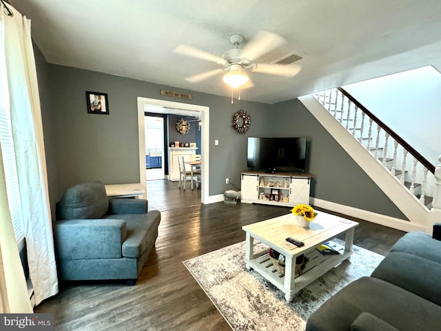 living room featuring dark wood-type flooring and ceiling fan