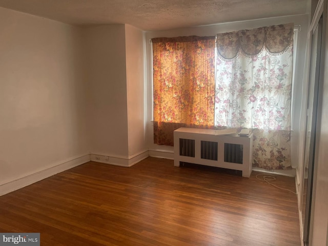 empty room with wood-type flooring and a textured ceiling