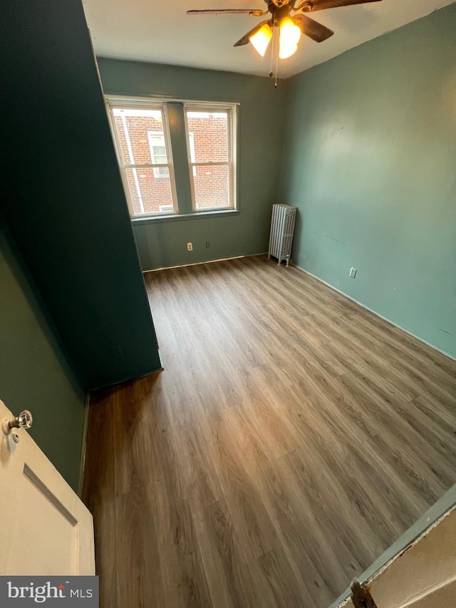 unfurnished room featuring wood-type flooring, radiator, and ceiling fan