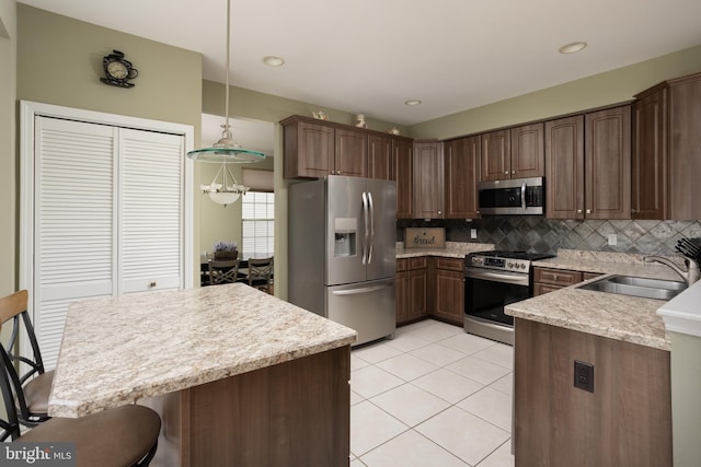 kitchen with sink, tasteful backsplash, dark brown cabinets, appliances with stainless steel finishes, and pendant lighting