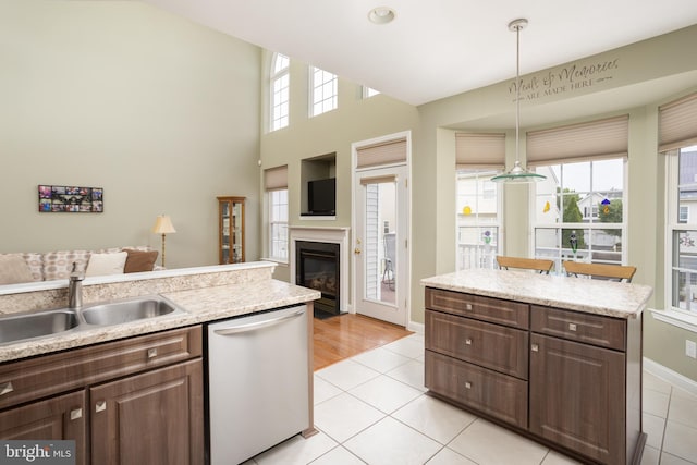 kitchen with pendant lighting, dishwasher, sink, light tile patterned floors, and dark brown cabinets