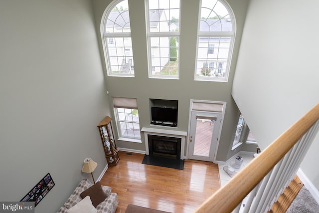 living room with a towering ceiling, a wealth of natural light, and light wood-type flooring