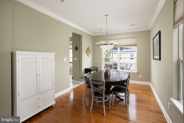 dining room with an inviting chandelier, crown molding, and hardwood / wood-style flooring