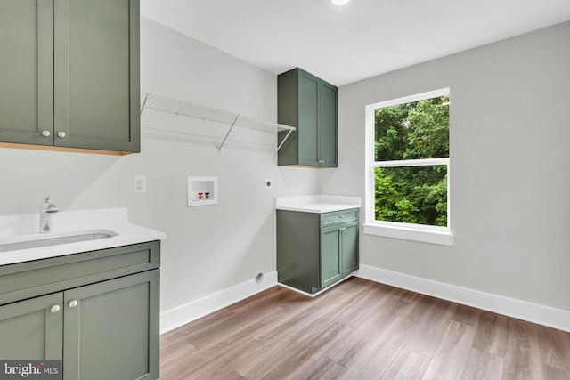 clothes washing area with light hardwood / wood-style floors, washer hookup, sink, electric dryer hookup, and cabinets