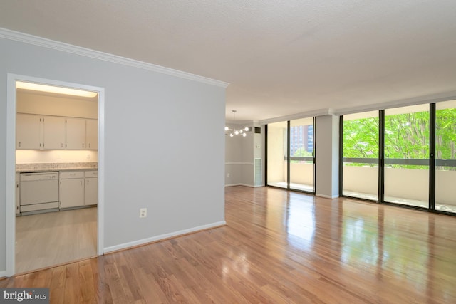 spare room with baseboards, light wood-style flooring, an inviting chandelier, expansive windows, and crown molding