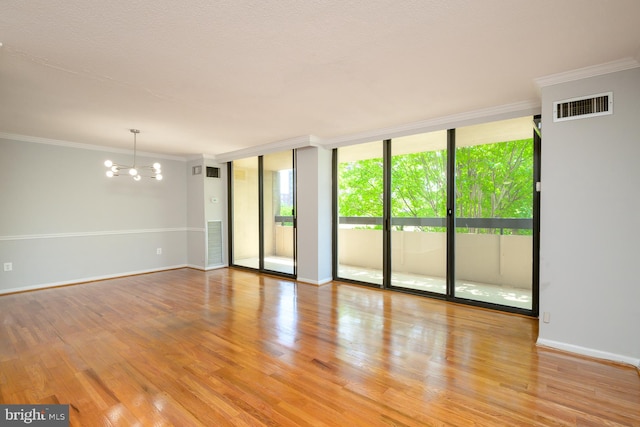 empty room with light wood finished floors, visible vents, ornamental molding, an inviting chandelier, and floor to ceiling windows