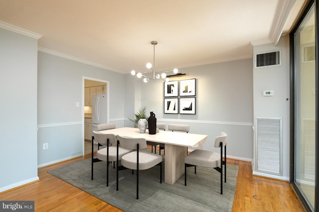 dining room featuring light wood finished floors, visible vents, and ornamental molding