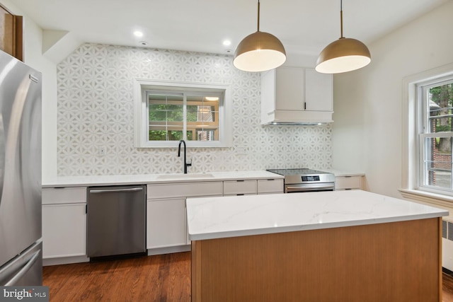 kitchen featuring pendant lighting, light stone counters, dark hardwood / wood-style floors, white cabinetry, and appliances with stainless steel finishes