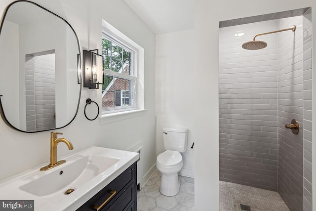 bathroom featuring tiled shower, vanity, and toilet