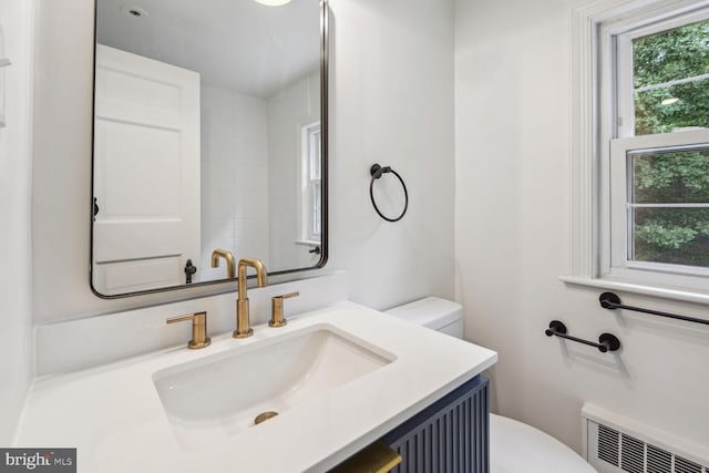 bathroom with vanity, toilet, and radiator