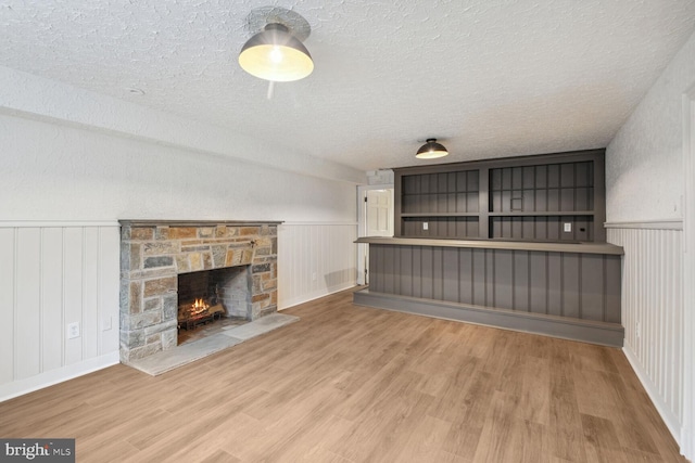 unfurnished living room featuring a textured ceiling, a fireplace, and hardwood / wood-style floors