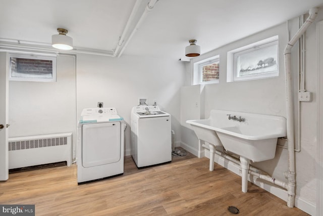 clothes washing area featuring light wood-type flooring, washer and clothes dryer, and radiator heating unit