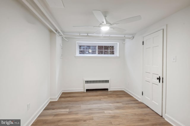 empty room featuring light wood-type flooring, radiator, and ceiling fan