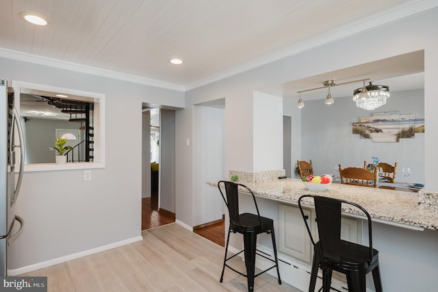 kitchen with a kitchen breakfast bar, light stone counters, ornamental molding, and light hardwood / wood-style floors