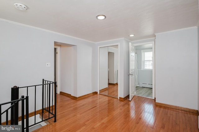 unfurnished room featuring light wood-type flooring, crown molding, and a baseboard radiator