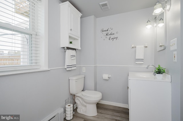 bathroom with toilet, a wealth of natural light, wood-type flooring, and vanity