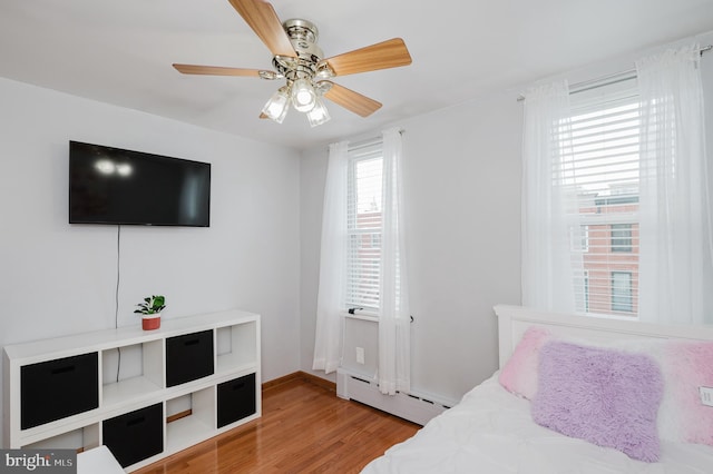 bedroom with ceiling fan, light hardwood / wood-style floors, and a baseboard radiator