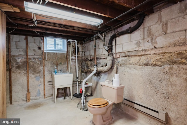 basement featuring a baseboard radiator and sink