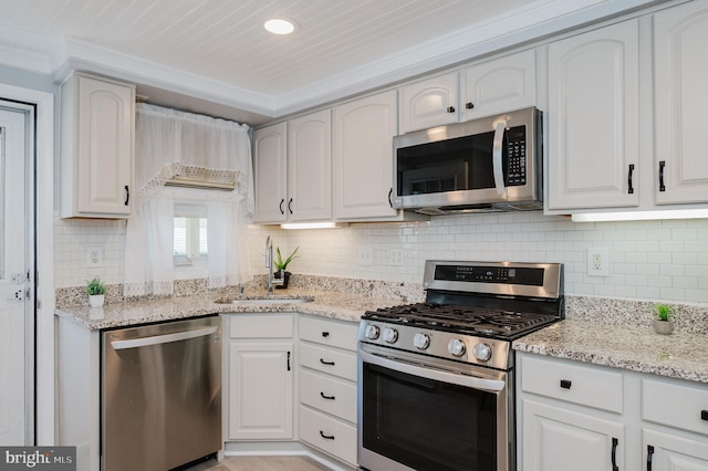 kitchen with light stone countertops, appliances with stainless steel finishes, white cabinetry, and sink