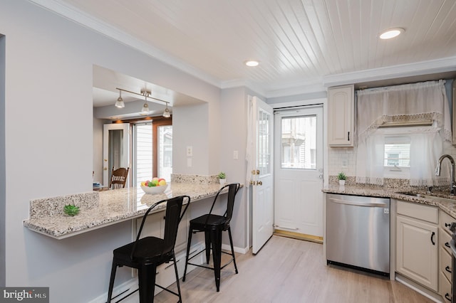 kitchen with a kitchen bar, sink, light stone counters, and stainless steel dishwasher