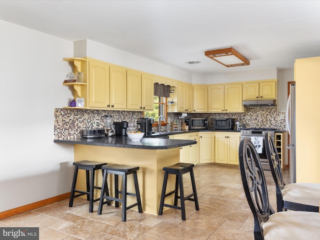 kitchen with a kitchen bar, tasteful backsplash, stainless steel appliances, sink, and light tile patterned floors