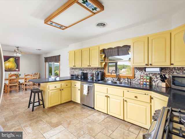 kitchen featuring sink, appliances with stainless steel finishes, a kitchen breakfast bar, decorative backsplash, and kitchen peninsula