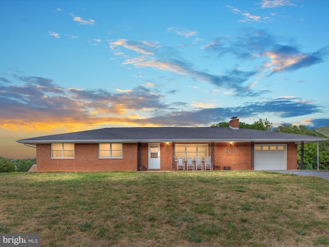 ranch-style house with a garage and a lawn