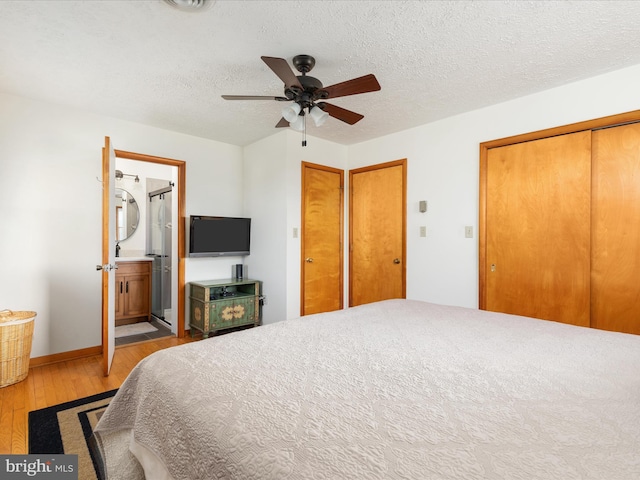 bedroom featuring a textured ceiling, light hardwood / wood-style flooring, ensuite bath, and ceiling fan