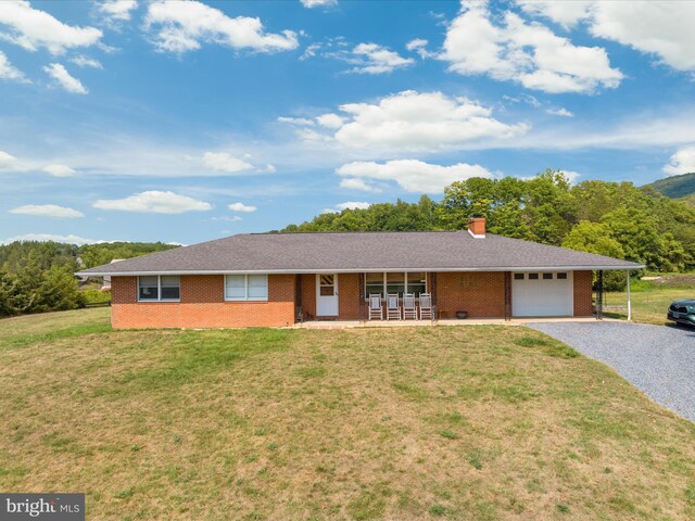 single story home with covered porch, a garage, and a front yard