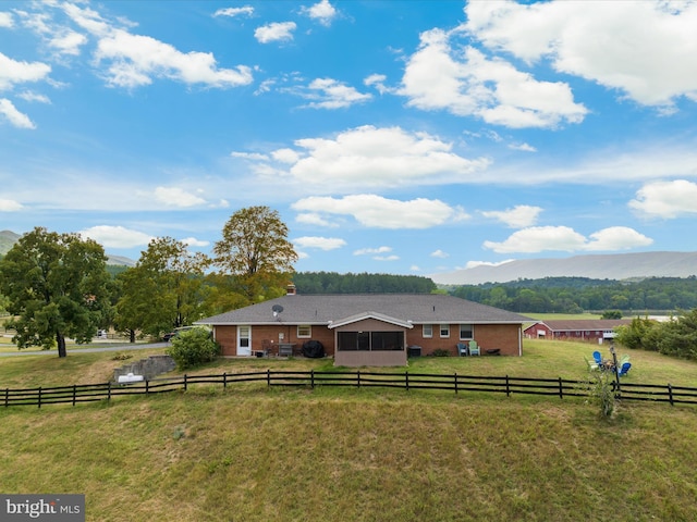 view of front of house with a mountain view, a front lawn, and a rural view