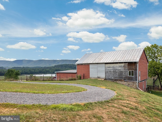 exterior space with an outbuilding, a mountain view, and a lawn