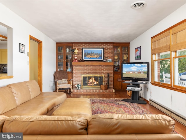 living room featuring brick wall, hardwood / wood-style flooring, a brick fireplace, and a baseboard radiator