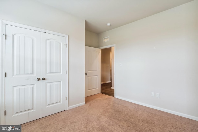 unfurnished bedroom with light carpet and a closet