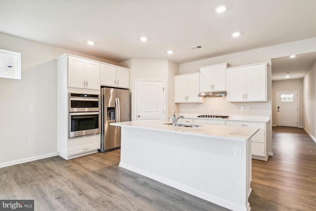 kitchen with white cabinetry, appliances with stainless steel finishes, a center island with sink, and light wood-type flooring