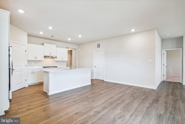 kitchen featuring white cabinetry, light hardwood / wood-style floors, sink, and a center island with sink